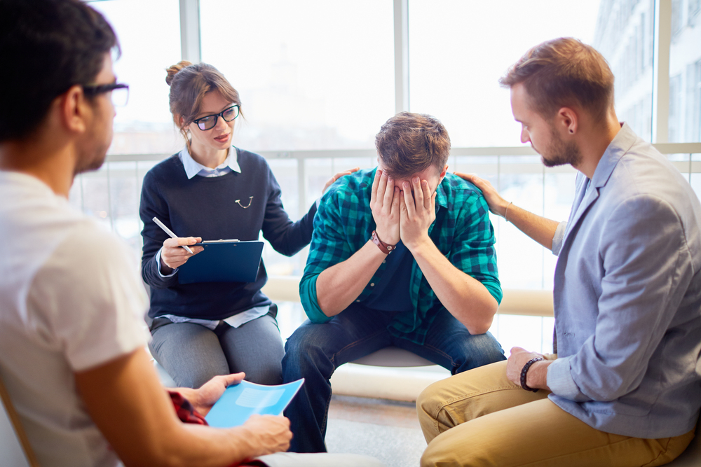 members of group therapy consoling a man with trauma