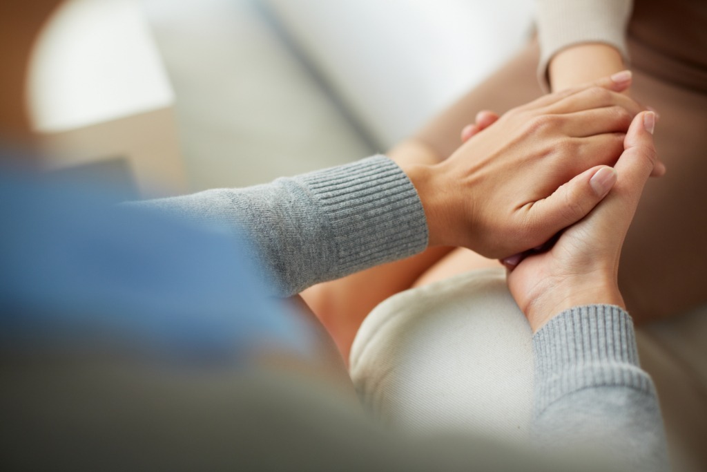 Two women clasping hands, representing support