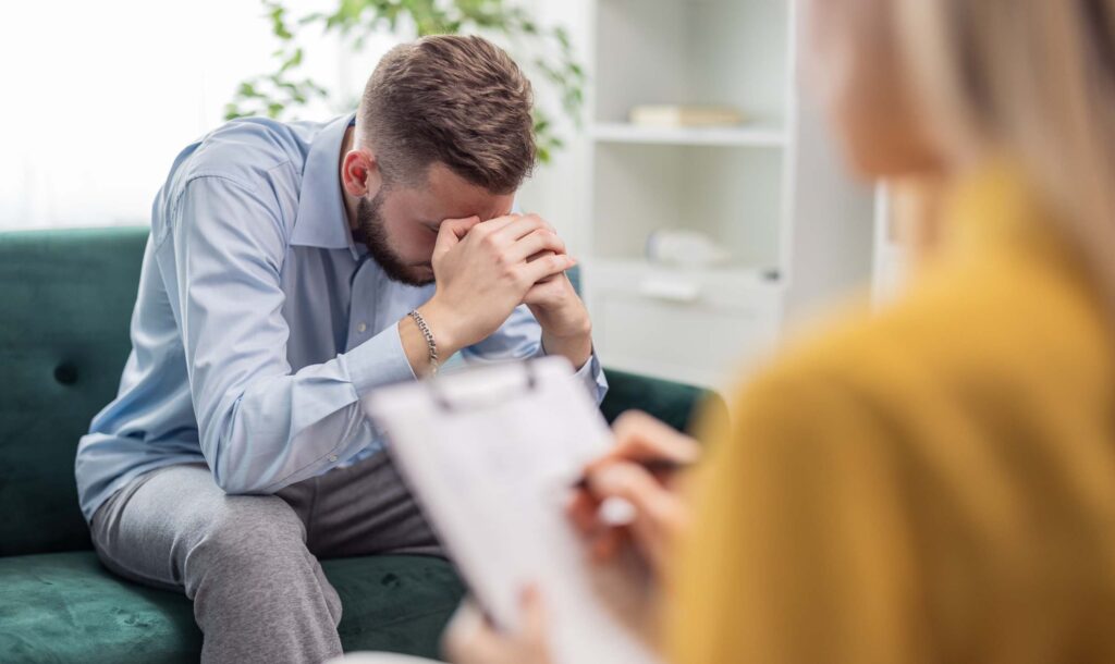 psychologist making notes during a therapy session with an alcoholic patient