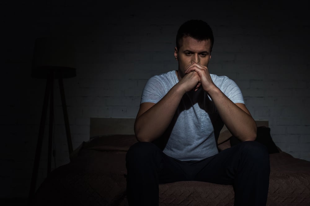 A man sitting in the dark, reflecting on his struggles with PTSD