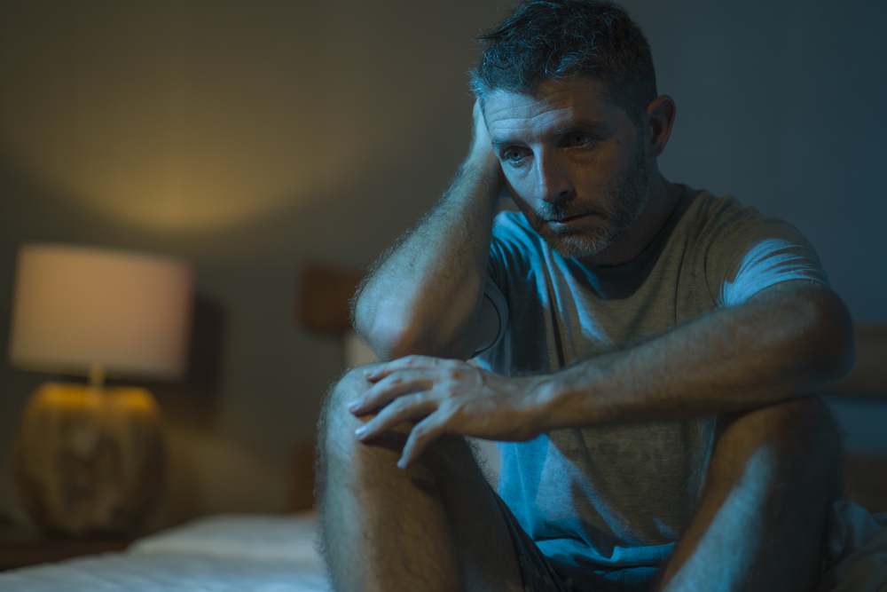 A man sitting in a dimly lit room, lost in thoughts of depression