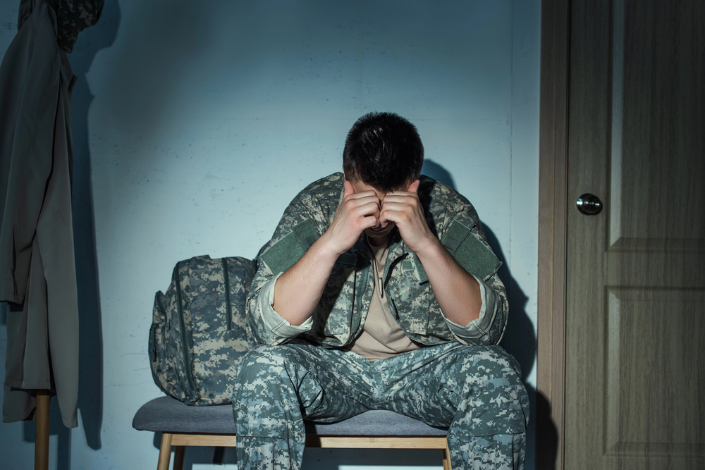 soldier seated with his head in his hands, dealing with PTSD