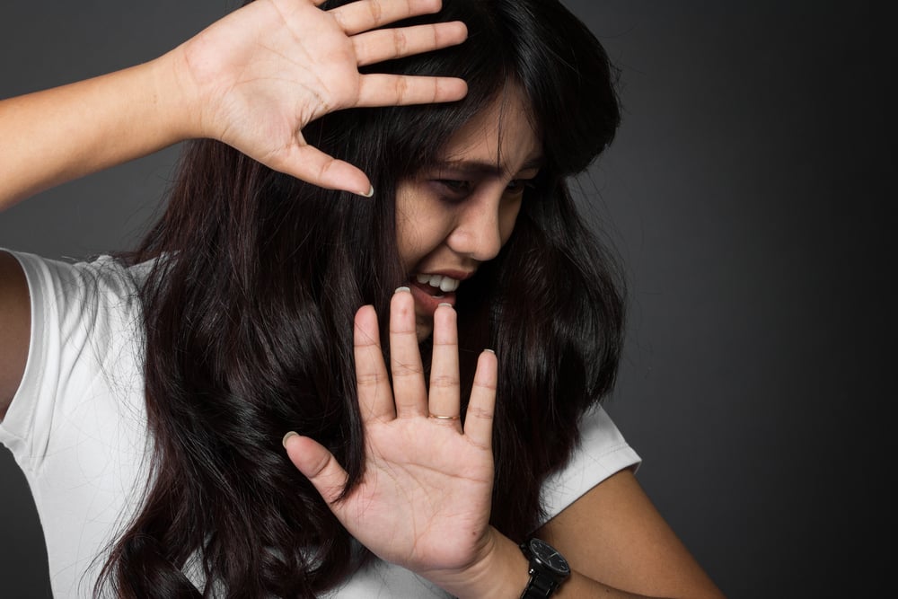 A woman shielding herself, showing fear and distress from PTSD