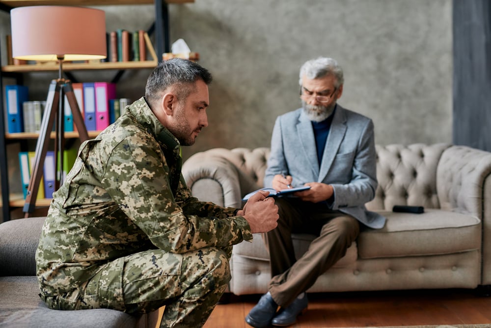 military man looking away during PTSD therapy session with psychologist