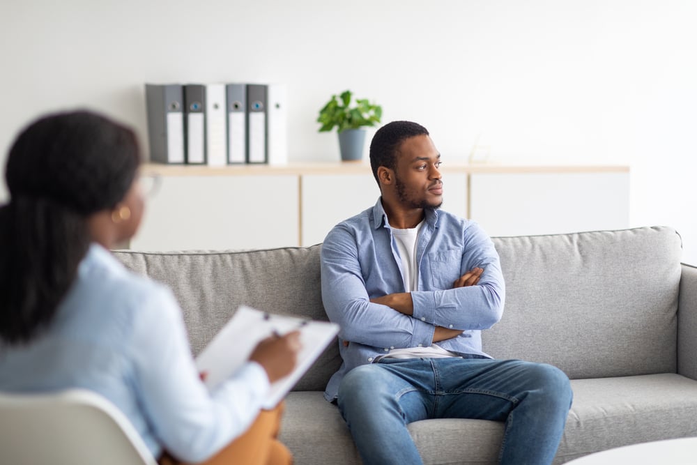 Professional psychologist working with emotionally detached black male patient at clinic, trying to help him with narcissistic behavior disorder