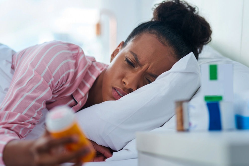 a woman holding a pill bottle while in bed