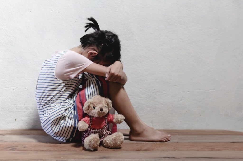 little girl sitting at the corner of the room feeling sad and lonely having childhood trauma