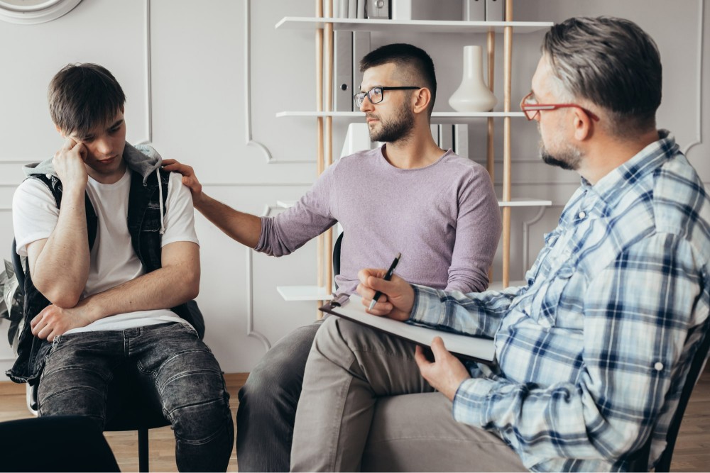 man tapping shoulder of a depressed young man