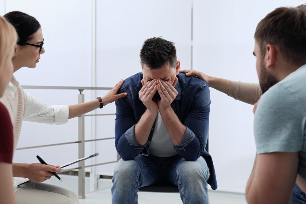 Psychotherapist working with group of drug addicted people at therapy session indoors