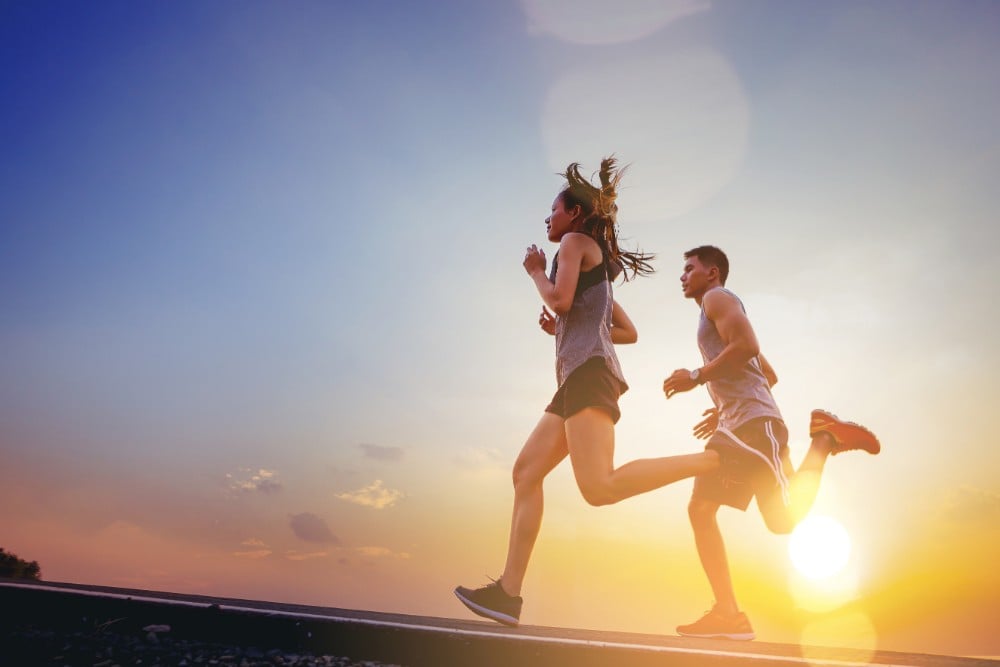 couple doing the morning run with the run raising in the background