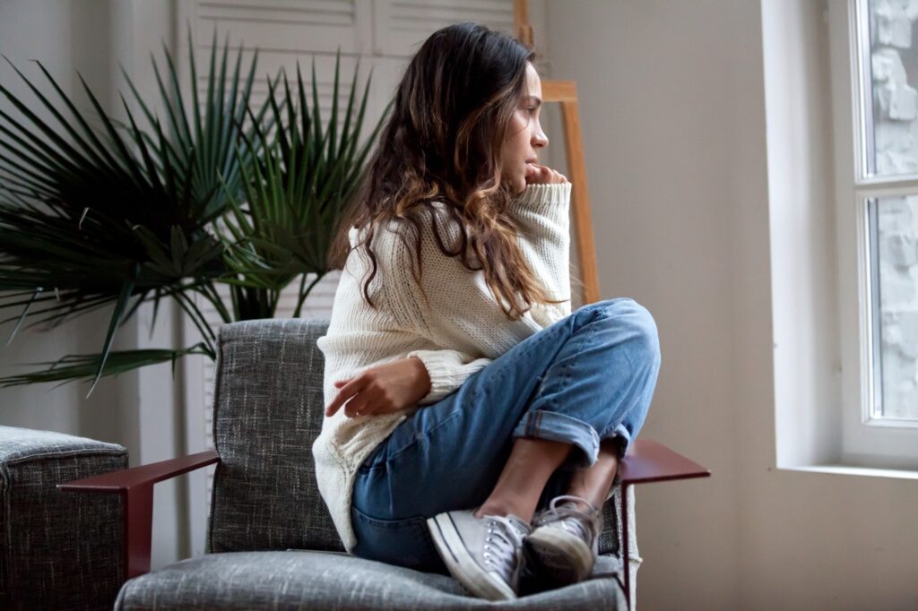 Sad thoughtful girl sitting on chair feeling depressed or lonely