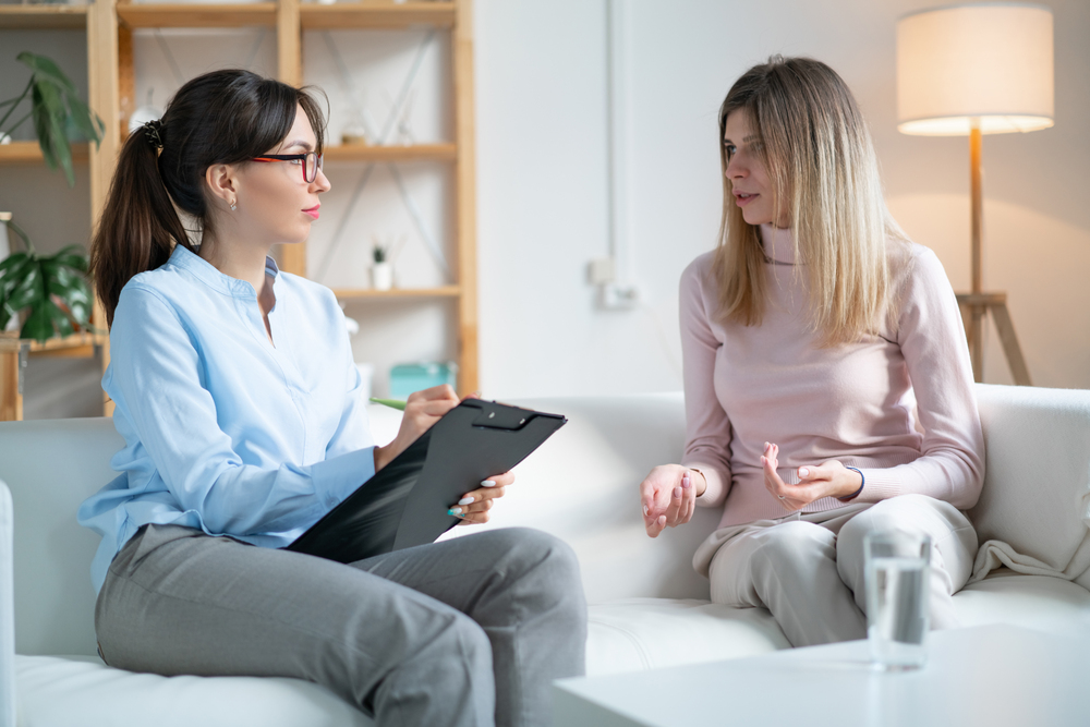 Patient talks about his problems to the Neurotherapist sitting sofa in office.