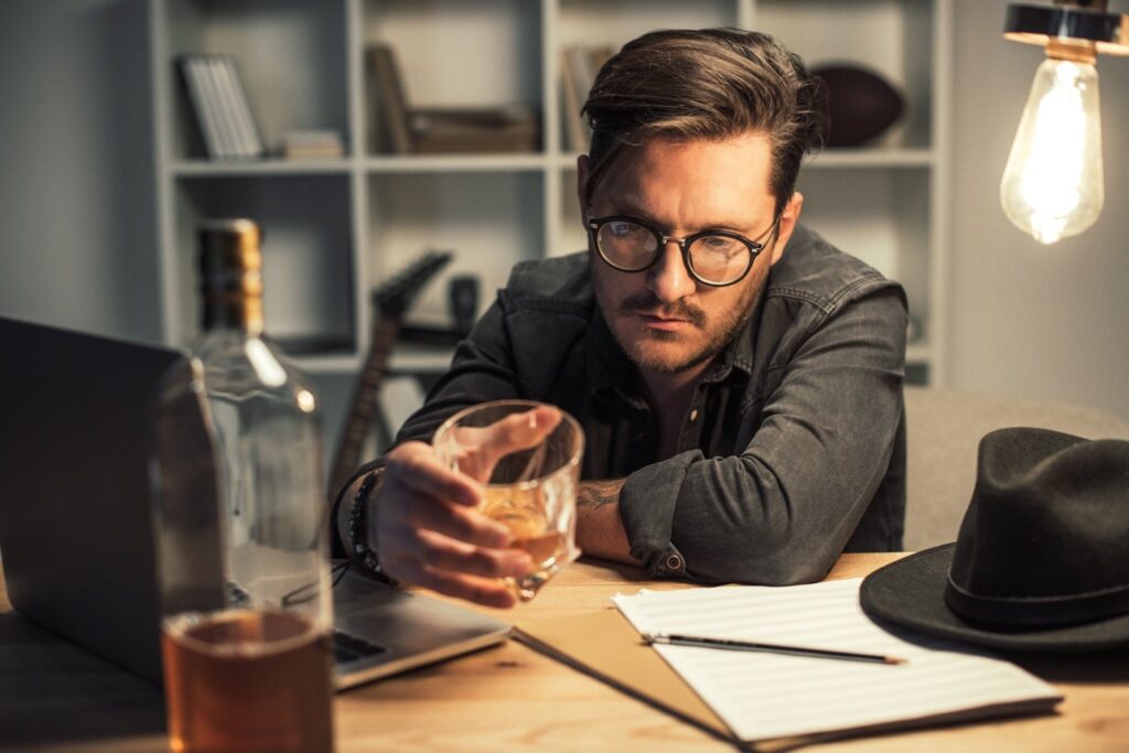 man holding scotch whisky showing sign of being alcoholic