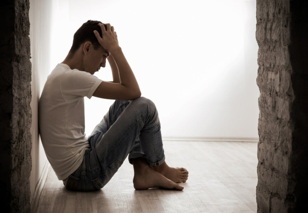 young man sitting down on the floor showing sign of major depressive disorder