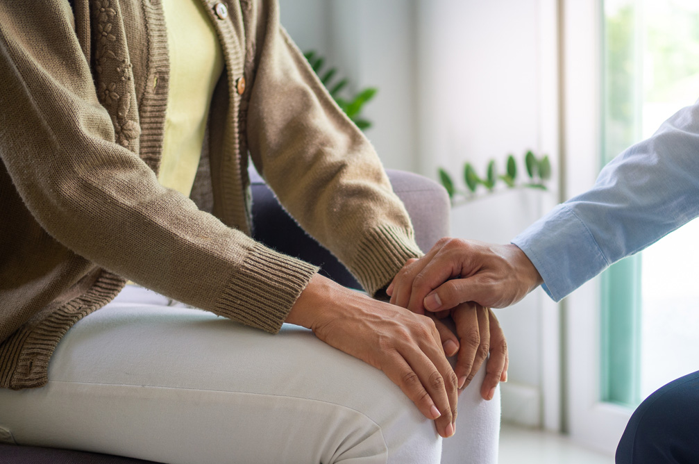 Man sitting on couch two people holding hands showing support for alcohol withdrawal 