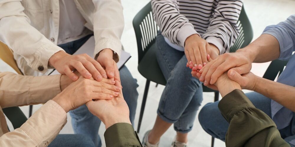 group therapy session where members hold hands